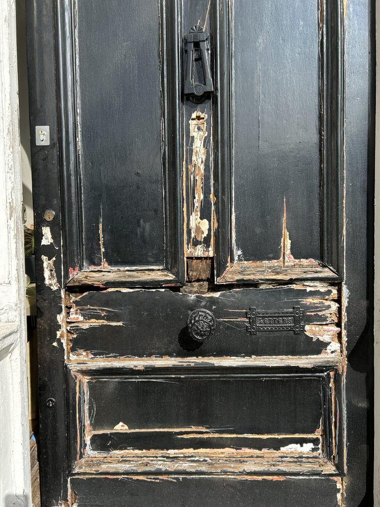 Original Victorian front door with peeling paint and timber rot before restoration