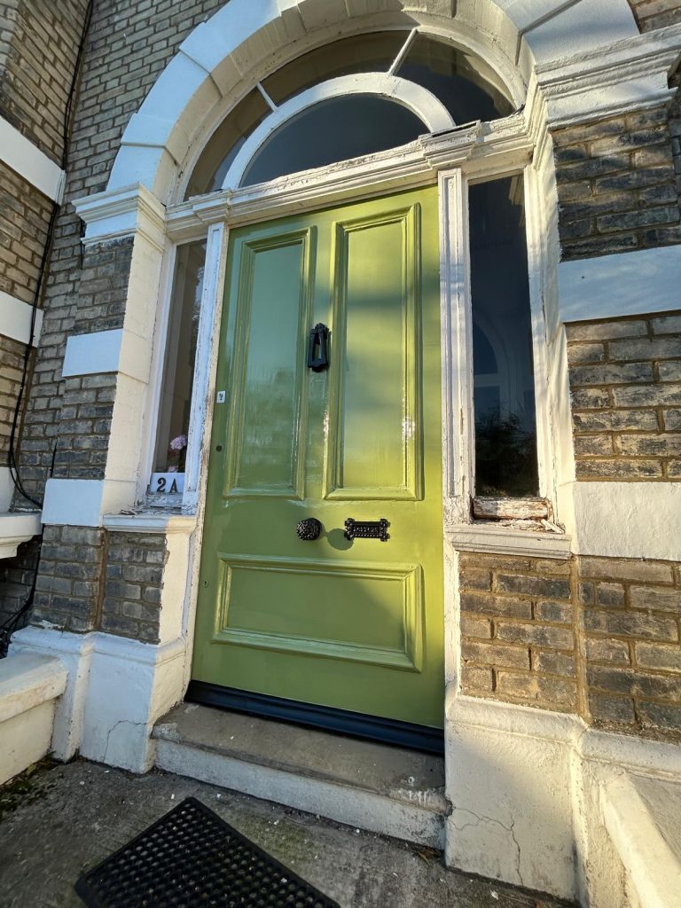 Bespoke heritage green gloss front door restoration with traditional black ironmongery.
