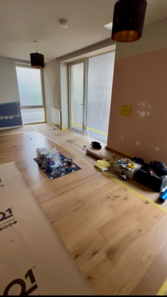 Professional interior spray painting preparation with full floor and furniture protection by Loveday Decorators.